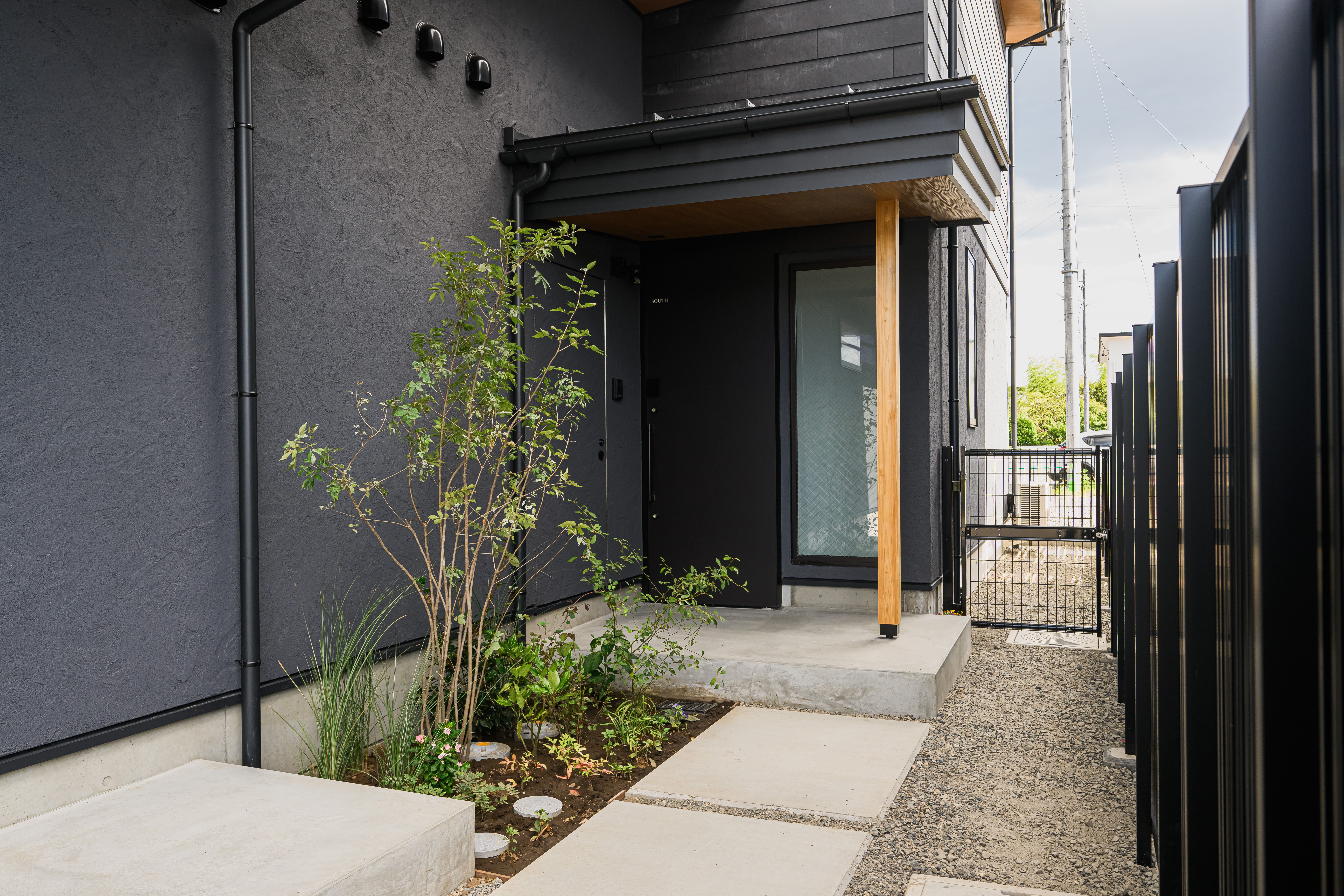 植栽と石のアプローチがある MOKUGO South Wing の玄関
