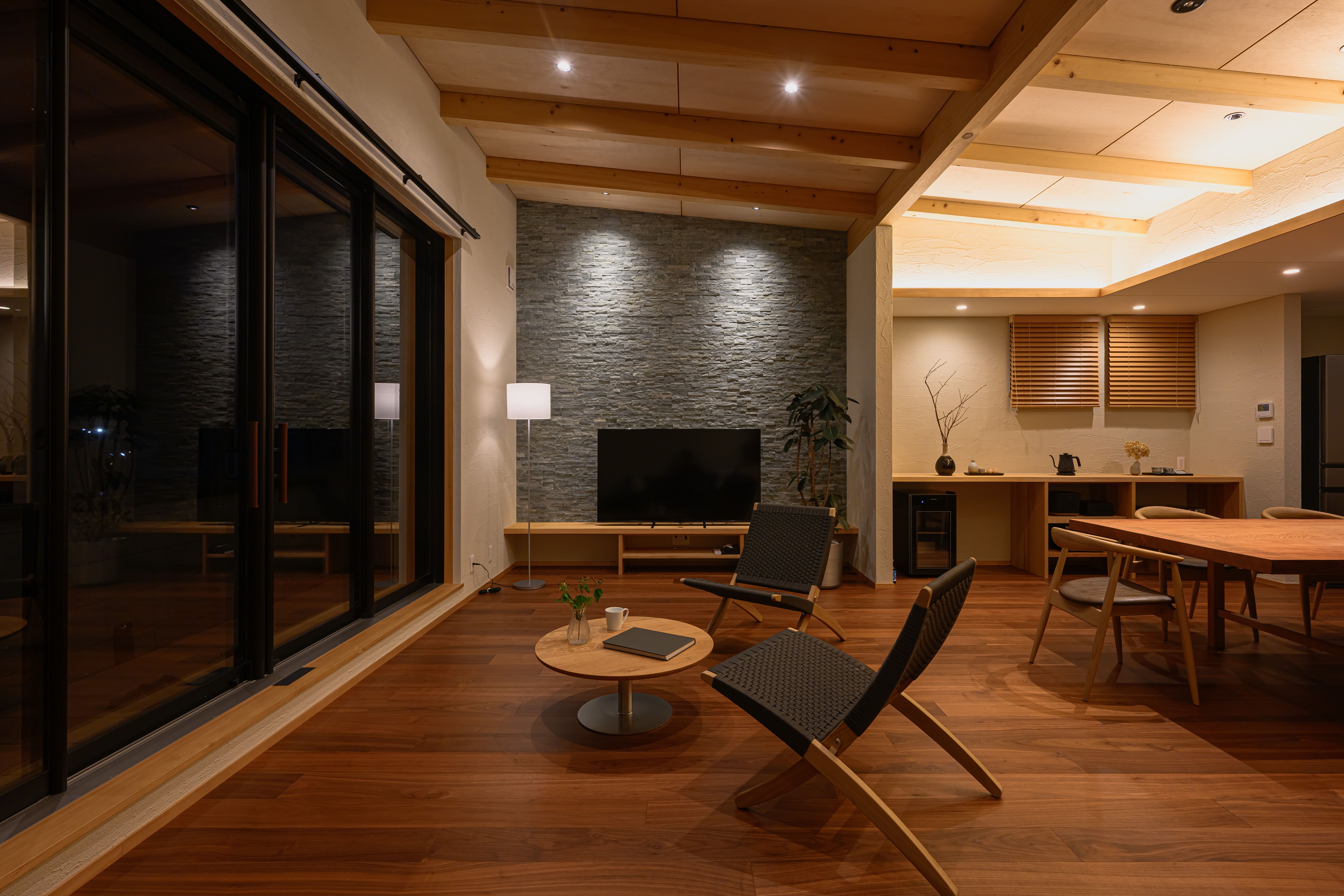 木の梁と家具が灯りに浮かぶ夜の South Wing